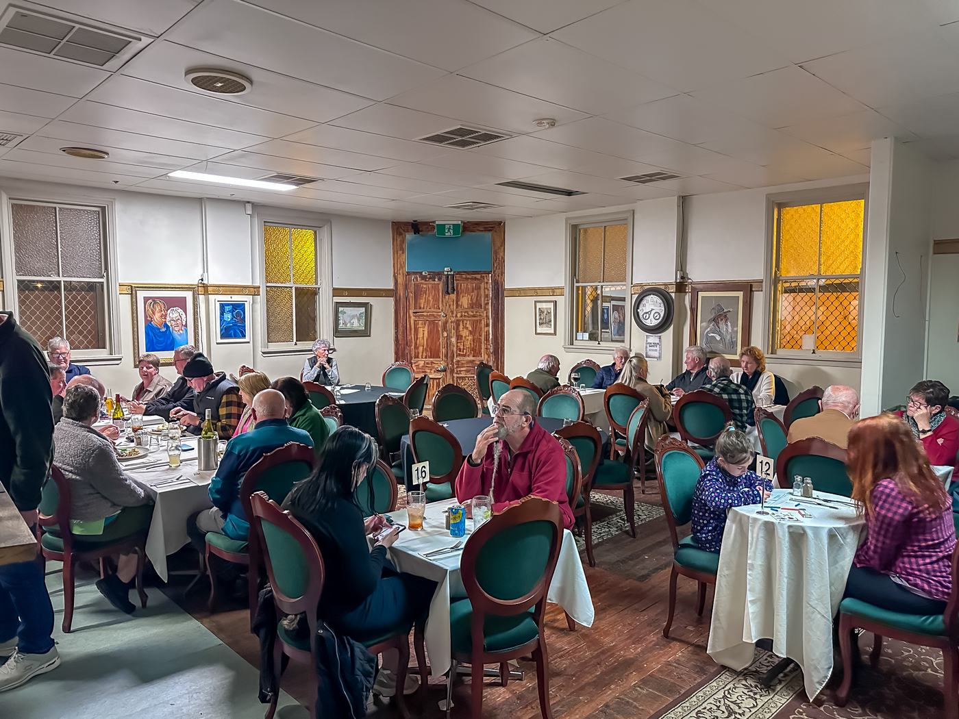 Guests at white-clothed tables in the Club Boutique Hotel dining room at dinner.
